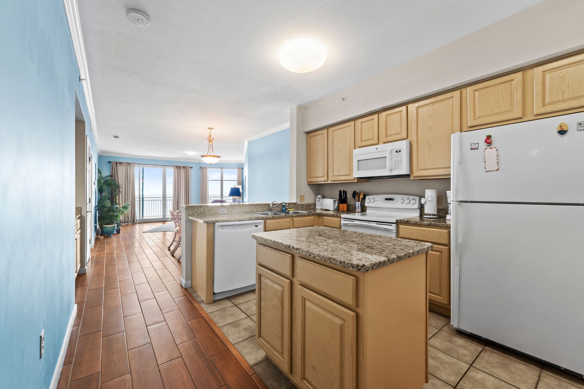 A kitchen with wooden cabinets, a white refrigerator, a microwave, and a dishwasher.