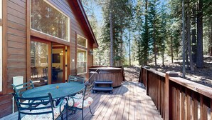 Un patio in legno con tavolo e sedie, una vasca idromassaggio e un recinto in legno.