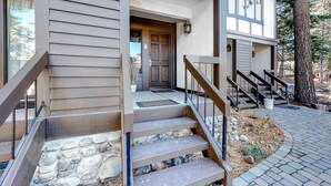 A modern building with a stone staircase, a wooden door, and a metal railing. - Ski getaway with amazing mountain views, fireplace, pool, & river path access (Olympic Valley)