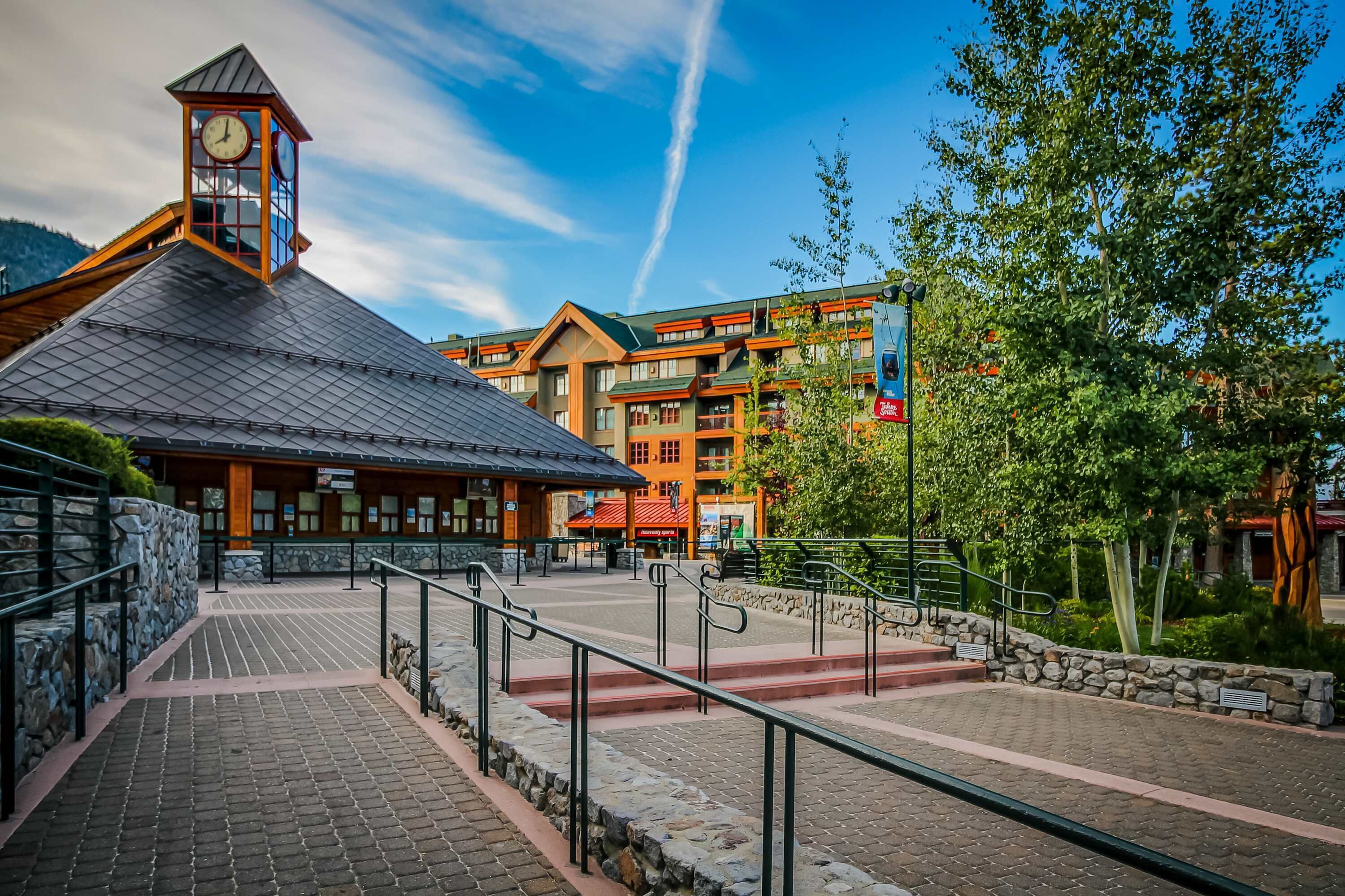 A lodge with a clock tower, stone steps, and a view of a mountain.
