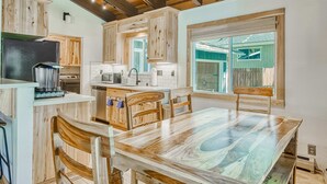 A kitchen with wooden cabinets, a dining table, and a large window. - Family Home with Fast WiFi, Wood Stove, Firepit, & Enclosed Yard - Dogs OK (South Lake Tahoe)