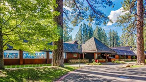 A lodge with a covered patio, large trees, and a clear sky. - Family Home with Fast WiFi, Wood Stove, Firepit, & Enclosed Yard - Dogs OK (South Lake Tahoe)