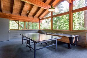 Ein Tischtennis-Tisch in einem Raum mit großen Fenstern und Holzbalken.