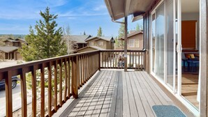 A wooden deck with a railing, a covered area, and a view of neighboring houses. - Centrally-Located Condo near Ski Resorts with Gas Fireplace (Truckee)