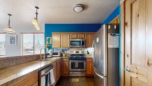 A kitchen with wooden cabinets, a stainless steel refrigerator, a microwave, and a stove. - Centrally-Located Condo near Ski Resorts with Gas Fireplace (Truckee)