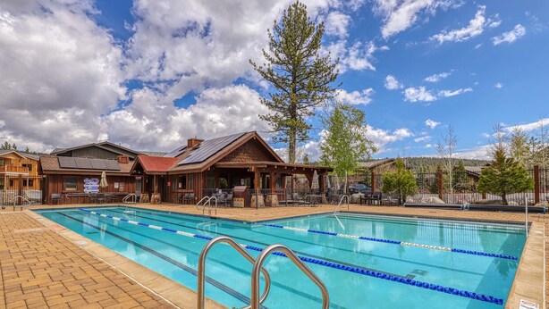 A swimming pool with clear lanes, a wooden deck, and a building with a covered patio in the background. - Centrally-Located Condo near Ski Resorts with Gas Fireplace (Truckee)