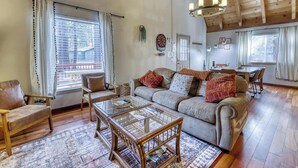 A cozy living room with a sofa, chairs, a glass coffee table, and a dining area with a table and chairs. - All-season, dog-friendly cabin with fireplace & deck - near Heavenly & beach (South Lake Tahoe)