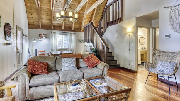 A cozy living room with a wooden ceiling, a sofa set, a glass coffee table, and a wicker chair. - All-season, dog-friendly cabin with fireplace & deck - near Heavenly & beach (South Lake Tahoe)