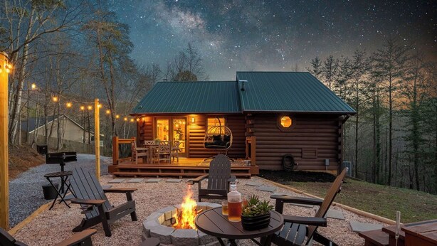 Eine Blockhütte mit einer Terrasse, Sitzgelegenheiten im Freien und einer Feuerstelle.
