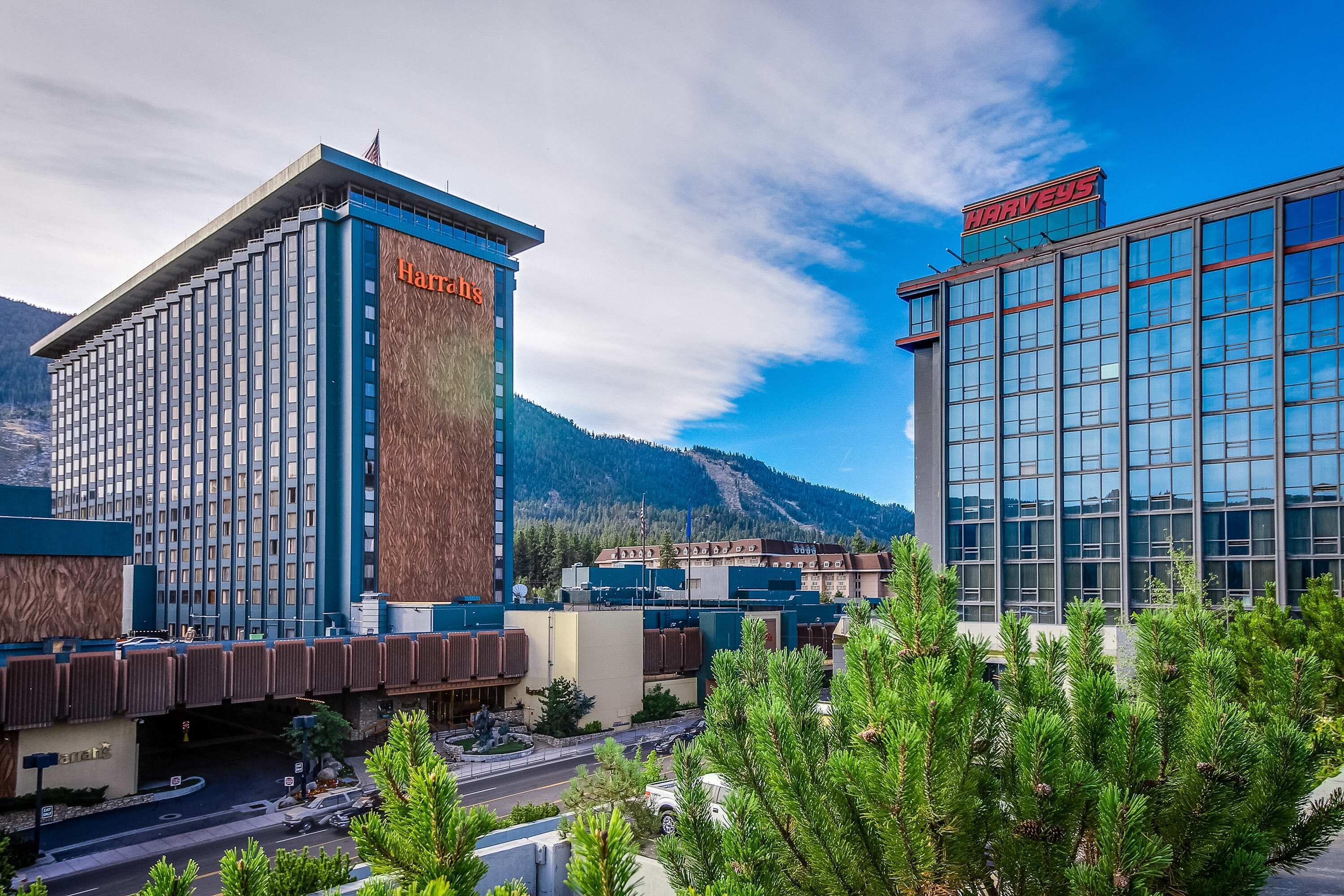 A hotel with a prominent Harveys sign, a modern glass building, and a mountainous backdrop.