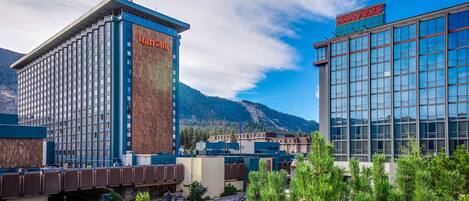 A hotel with a prominent Harveys sign, a modern glass building, and a mountainous backdrop.