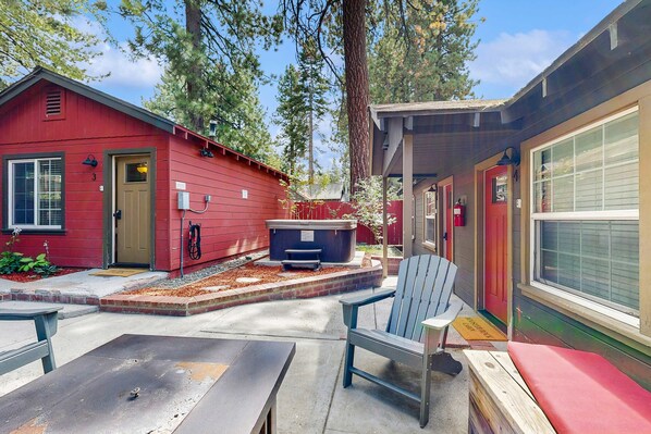 Une cabane rouge dotée d’un patio, d’un bain à remous et d’un fauteuil Adirondack bleu.