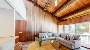 Un intérieur moderne avec un plafond en bois, une table à manger avec des chaises, un canapé et une grande fenêtre.