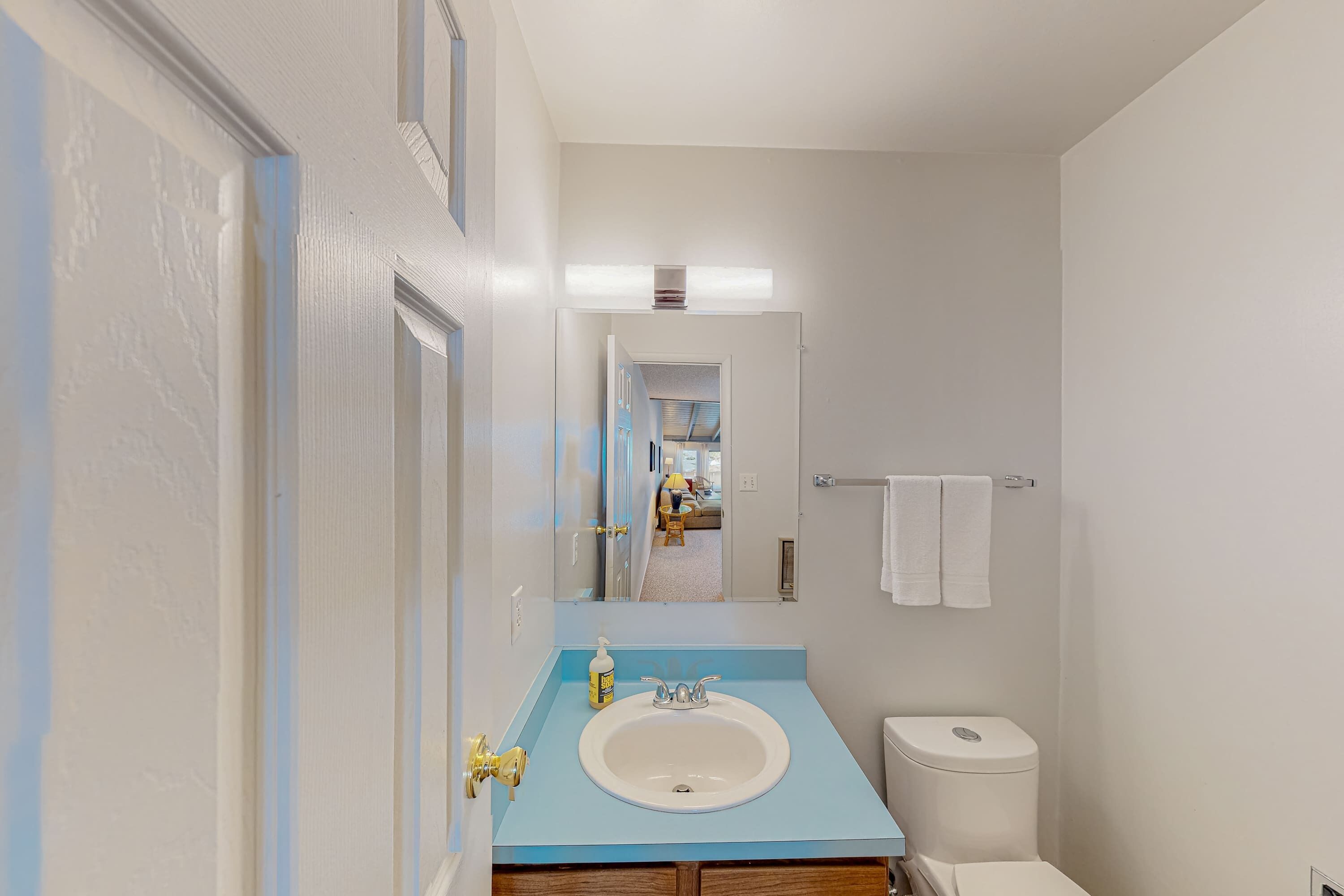 Un baño con encimera azul, lavamanos blanco y un inodoro.
