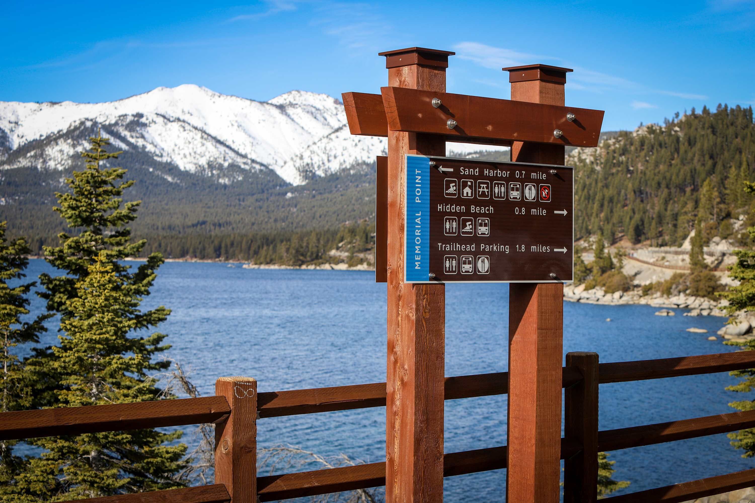 A wooden signpost with directional information for Sand Harbor, Hidden Beach, and Trailhead Parking.