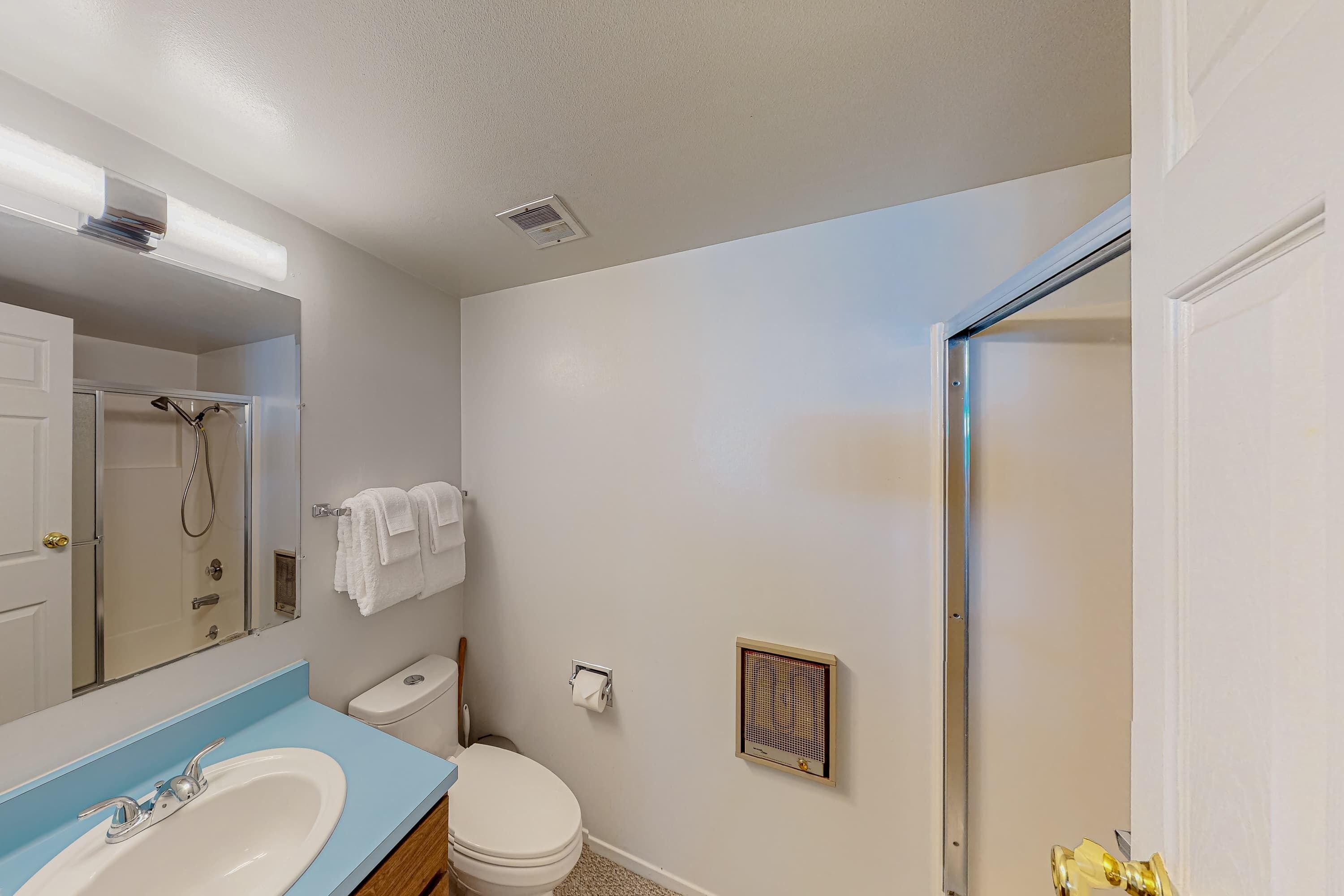 Un baño con lavabo, inodoro, ducha y toallero.