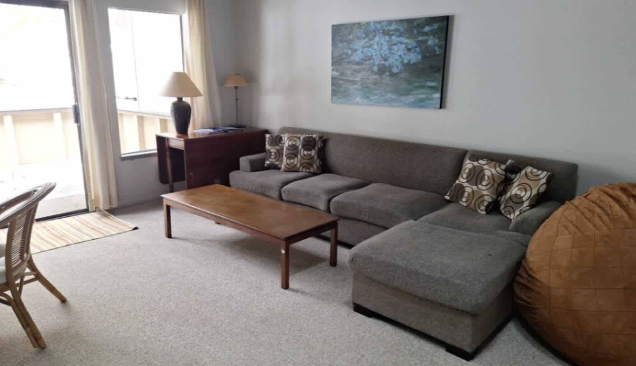 A living room with a sofa, a wooden coffee table, a lamp, and a painting on the wall.