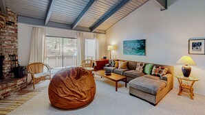 A living room with a fireplace, a sofa, a coffee table, a bean bag, and a lamp. - Dog-friendly condo with pool access, fireplace, private washer&dryer, & wet bar (Incline Village)