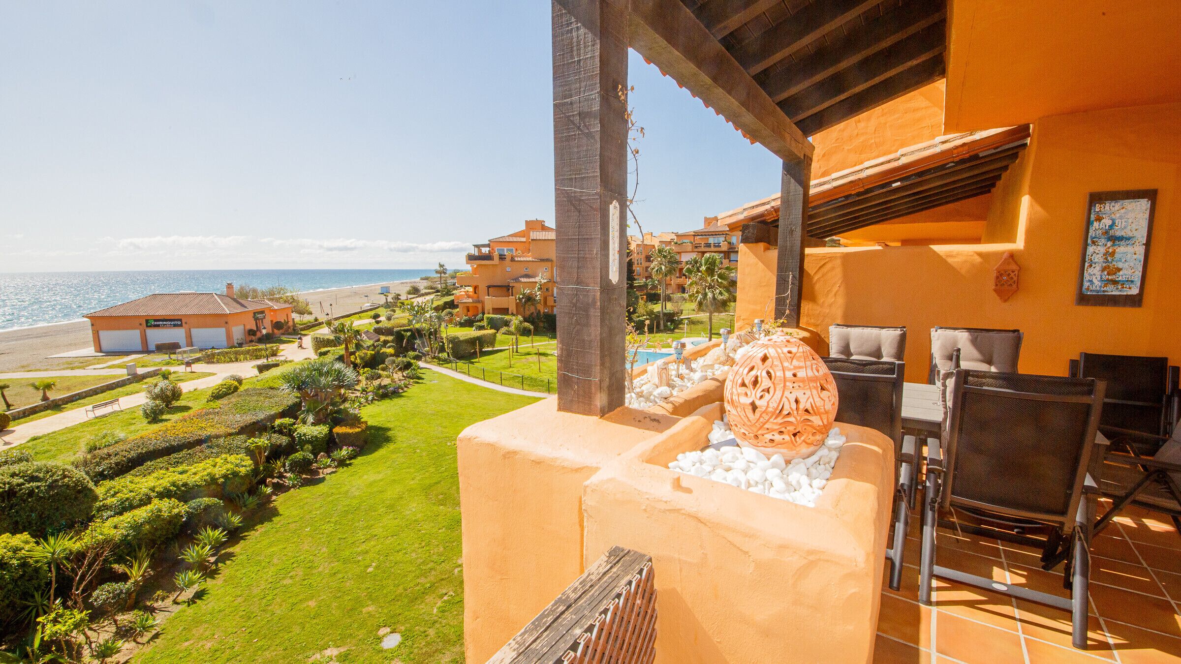 Un balcon avec vue sur la plage, une piscine et un bâtiment portant une enseigne.