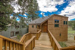 A wooden cabin with a wooden staircase leading to a door, surrounded by trees. - Home with amazing views, outdoor dining, fireplaces, pool- dogs ok (Truckee)