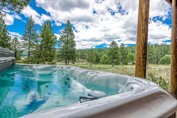 A hot tub with a clear view of a forested landscape and a golf course in the background. - Home with amazing views, outdoor dining, fireplaces, pool- dogs ok (Truckee)