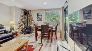 Una sala de estar con pared de piedra, chimenea, mesa de comedor y sillas.