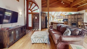 A spacious living room with a large flat-screen TV, a leather sofa, and a wooden ceiling. - Inviting home in Northstar Ski Resort with private hot tub & sauna, pool access (Truckee)