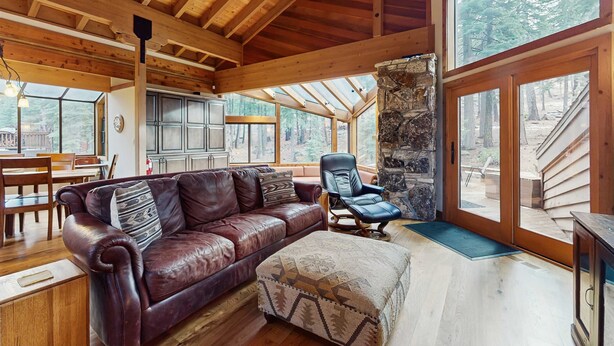 A wooden interior with a leather sofa, a stone pillar, and large windows. - Inviting home in Northstar Ski Resort with private hot tub & sauna, pool access (Truckee)