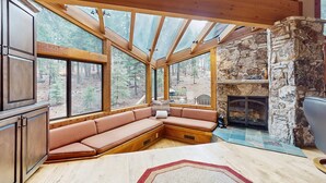 A cozy cabin interior with a stone fireplace, wooden beams, and a built-in bench with cushions. - Inviting home in Northstar Ski Resort with private hot tub & sauna, pool access (Truckee)
