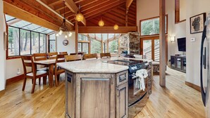 A spacious kitchen with wooden beams, a large island, and a stone fireplace. - Inviting home in Northstar Ski Resort with private hot tub & sauna, pool access (Truckee)