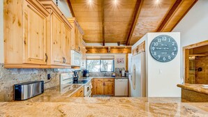 Una cocina con armarios de madera, un tostador de acero inoxidable, un reloj y un letrero que dice 'EAT, SLEEP, SKI'.