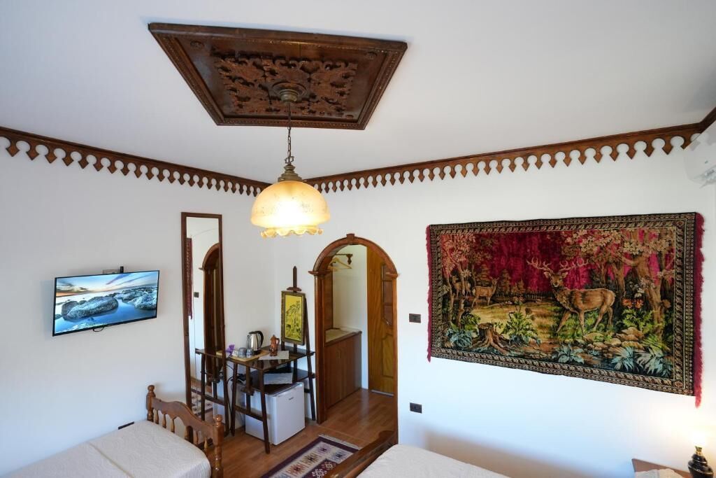Una habitación con una cama, un escritorio, un televisor, un espejo y un tapiz.