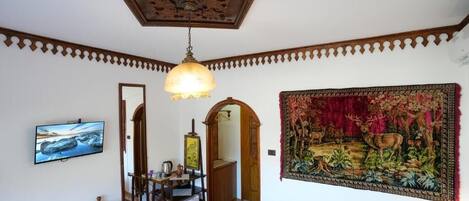 Una habitación con una cama, un escritorio, un televisor, un espejo y un tapiz.