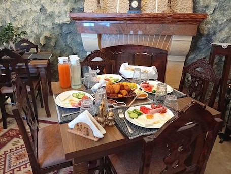 A breakfast table set with plates of food, glasses, and a clock on the wall.