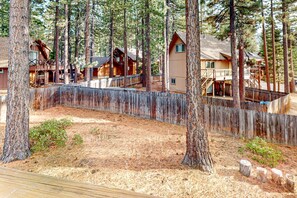 Une zone boisée avec des cabanes en bois, une terrasse en bois et une clôture en bois.
