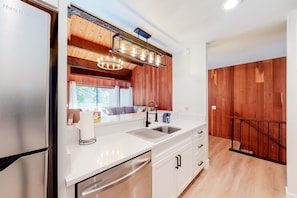 A kitchen with a stainless steel refrigerator, white cabinets, a sink, and a wooden ceiling. - Mountain Home with Gas Fireplace, Fast WiFi, Balcony, Shared Pool, Tennis (Kings Beach)