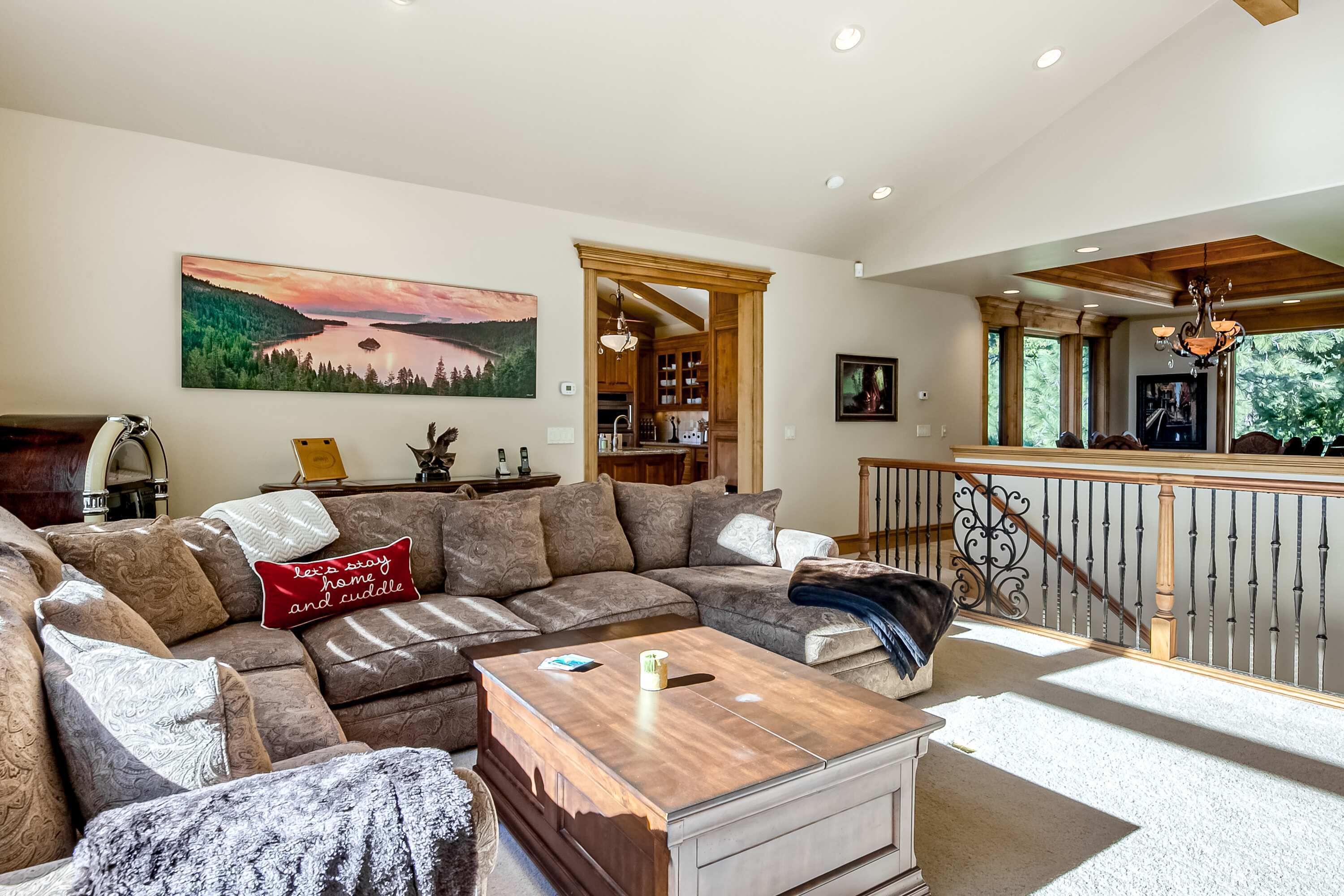 A living room with a sectional sofa, a coffee table, and a painting of a landscape.