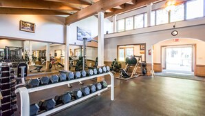 Ett gym med utrustning för styrketräning, speglar och ett stort fönster.