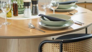Une table à manger avec des assiettes, des verres et un vase rempli de tulipes rouges.