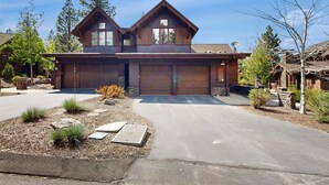 Uma casa de dois andares com garagem, entrada por acesso e jardim frontal bem cuidado.