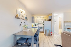 A modern kitchen with white cabinets, a microwave, and a stainless steel refrigerator.