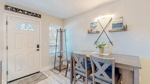 A dining area with a wooden table and chairs, a wall-mounted shelf with decorative items, and a door with a frosted glass window. - Tranquil condo in Stateline, sleeps 4 (Stateline)