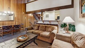 Un salon confortable avec un canapé, des fauteuils, une table basse et une lampe.