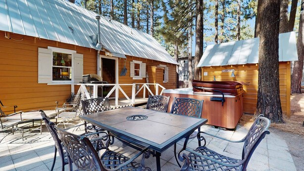 Una cabaña con un patio, mobiliario exterior y un jacuzzi.