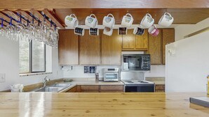A kitchen with wooden cabinets, a countertop, a sink, a microwave, a toaster, and hanging cups. - Spacious home with incredible views, full kitchen, shared  pool & tennis courts (Incline Village)