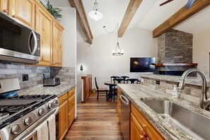 A kitchen with wooden cabinets, a granite countertop, a built-in stove, and a stone fireplace. - Inviting condo with gas fireplace & grill, sleeps 8 (Zephyr Cove)