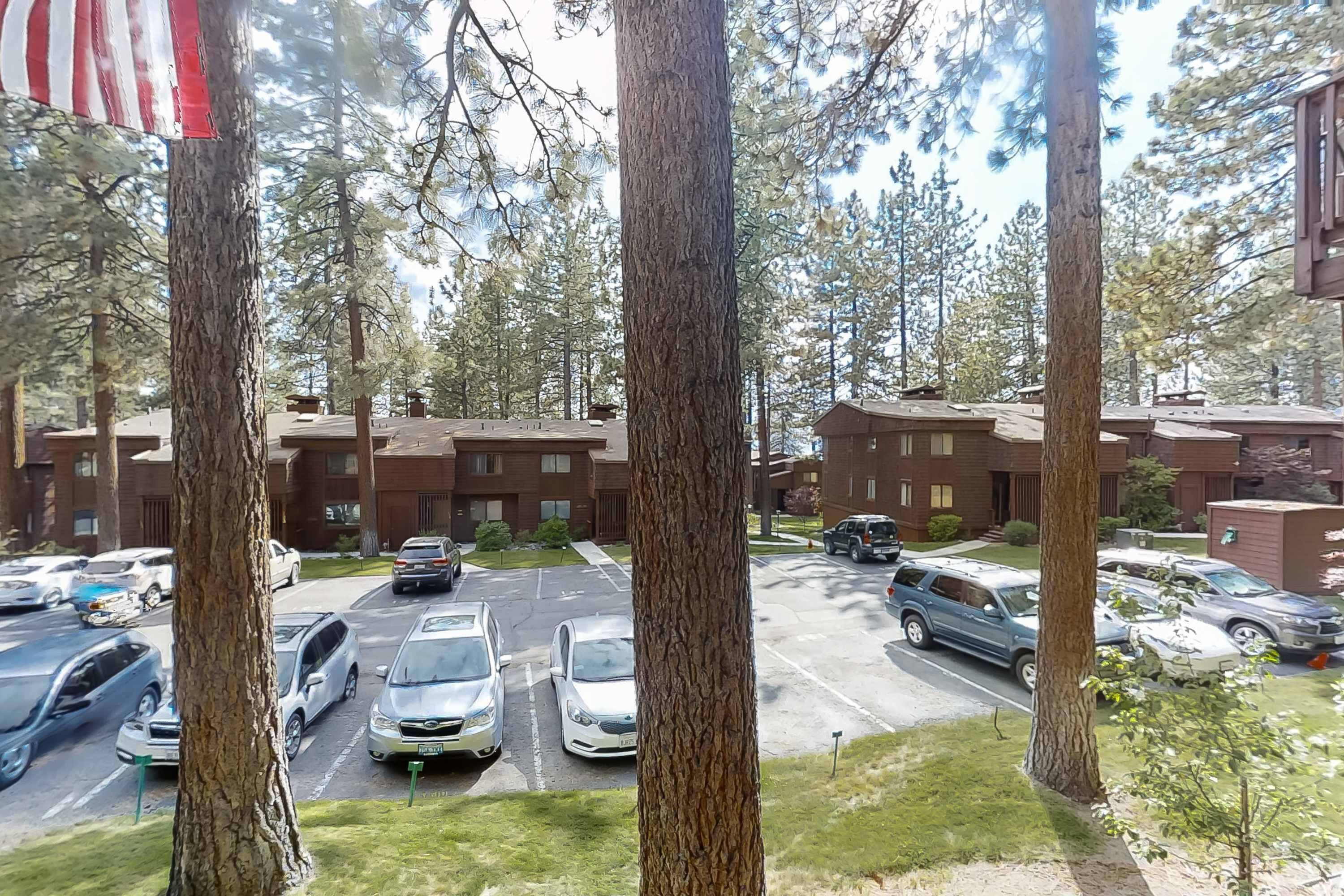 A parking lot with several cars, trees, and a building with a brick facade.