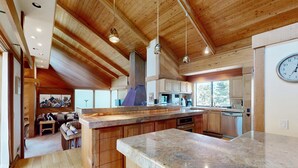 Una cucina moderna con mobili in legno, piani in granito e un'isola grande.