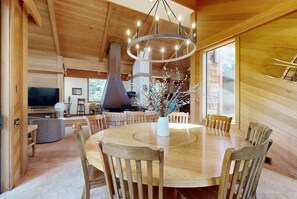 A wooden interior with a round dining table, chairs, a chandelier, and a fireplace. - Enchanting alpine retreat near skiing with games & fireplace - dog-friendly (Truckee)