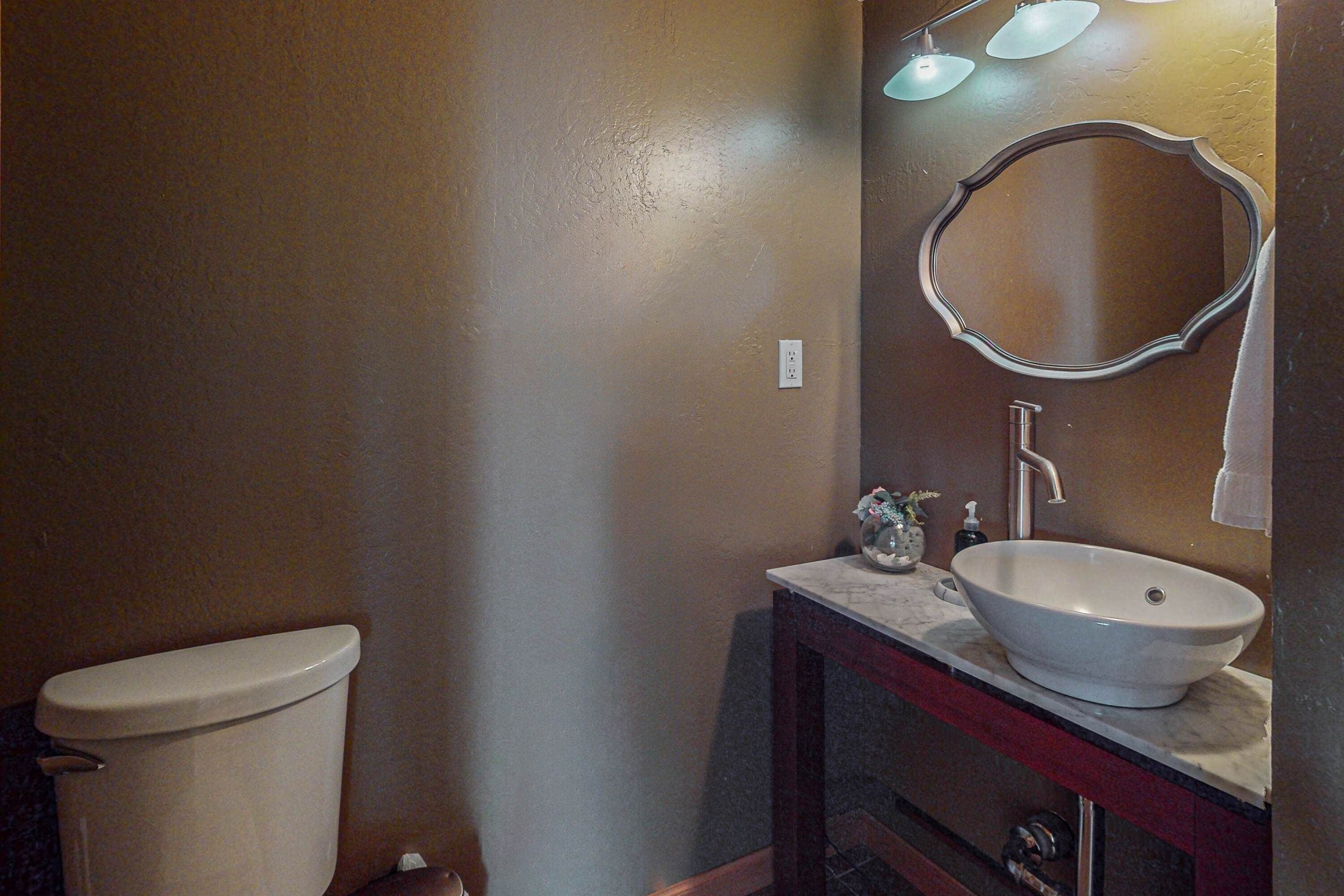 A bathroom with a toilet, a sink with a mirror above it, and a towel hanging on the wall.